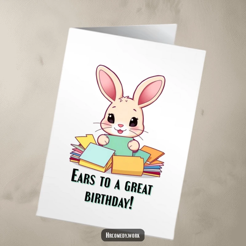Funny free printable birthday card: A large-eared rabbit meticulously sorts colorful papers, looking slightly overwhelmed but cheerful.